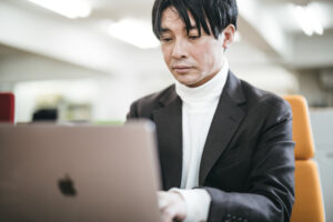 男性が真剣な表情でパソコンを見つめ作業